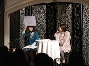 頭上にフリップを掲げて知られざるエピソードを次々と話すつじあやの(写真左)。