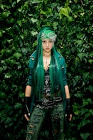 背景の樹木に溶け込むような、全身グリーンのファッションを着こなすJASMINE。