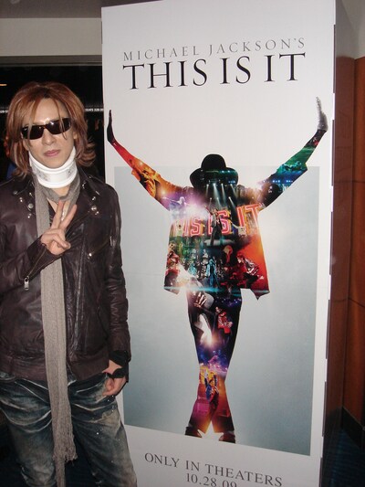 「THIS IS IT」の立て看板の前で、ピースサインを見せるYOSHIKI。