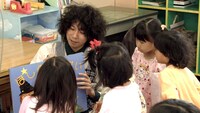 園児に囲まれながら紙芝居をする“たっくすまん”。