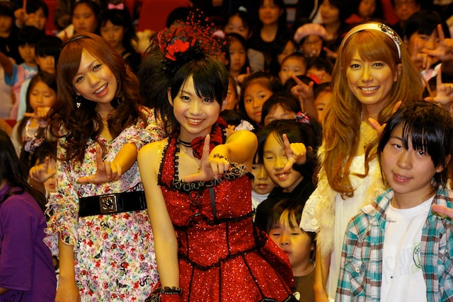 笑顔の子供たちとともに記念撮影をする虎南有香（写真左）、北神未海（中央）、里田まい（右）。