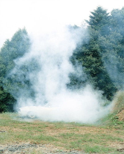 煙に包まれた白い車。