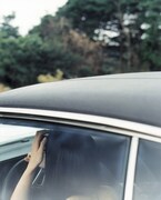 車の中に女性。ハンドルに右手をかけている。