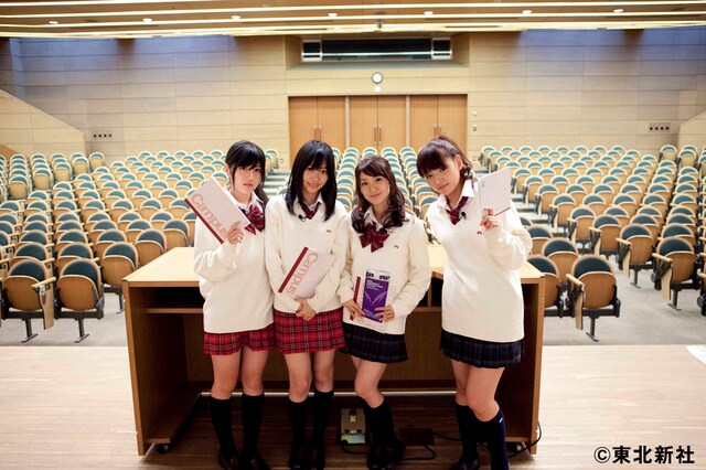 500人分のイスがずらりと並ぶ講堂。キャンパスノートを手にニッコリとほほえみ、一見リラックスしているように見える4人だが……。(C) 東北新社
