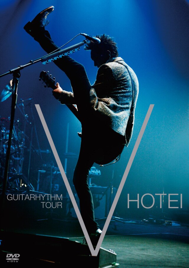 写真はDVD「GUITARHYTHM V TOUR」ジャケット。スラリと長い足を高く上げた姿が「V」の字に。ちなみに布袋の身長は公称187cm。つまり、つま先の高さはゆうに2mを超えている。