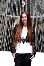 個性的なクリスマスツリーの前でほほえむ傳田真央。