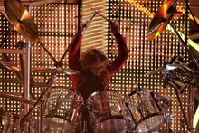 ドラムセットの前に座り、構えるYOSHIKI。