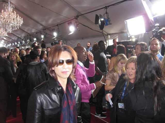 革ジャンにスカーフをあわせたシンプルな着こなしで、報道カメラに向けおだやかな視線を送るYOSHIKI。