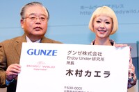 グンゼ株式会社平田弘代表取締役から「Enjoy Under研究所」所長の特大名刺を受け取ったカエラ。