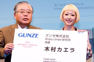 グンゼ株式会社平田弘代表取締役から「Enjoy Under研究所」所長の特大名刺を受け取ったカエラ。