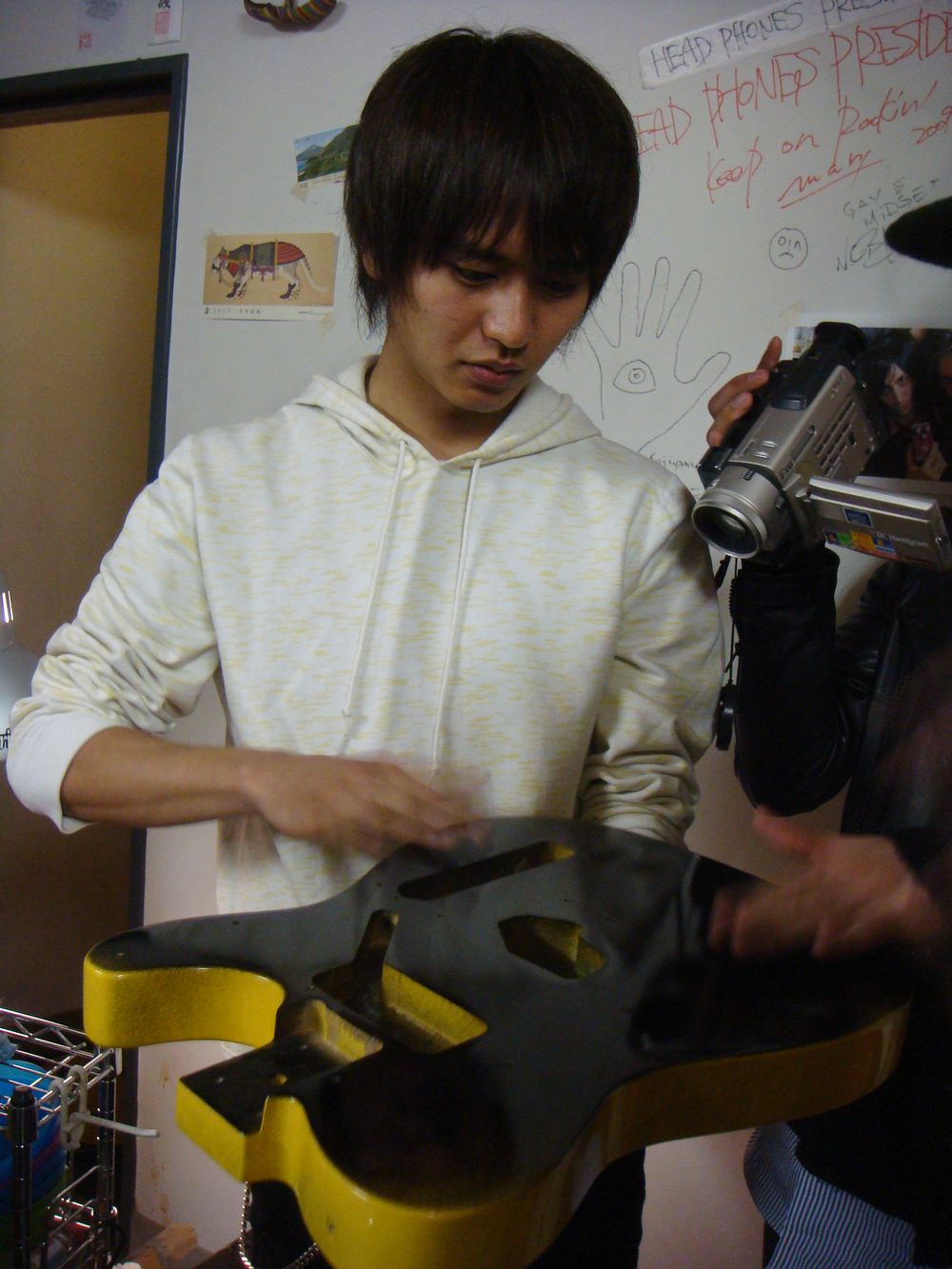 真剣な表情でギターに触る古村大介（G）。強度を確かめているのだろうか。