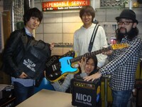 完成したカスタムギターを披露する4人。ボディにはNICOの文字、ギターケースとアンプにはNICO Touches the Wallsのロゴがプリントされている。