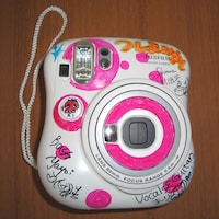 ホワイト×ピンクのカラフルなチェキ本体にはメンバーのサインが。