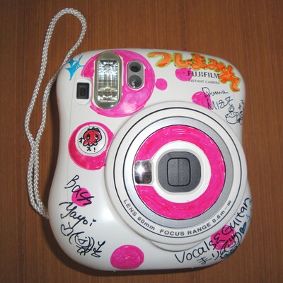 ホワイト×ピンクのカラフルなチェキ本体にはメンバーのサインが。