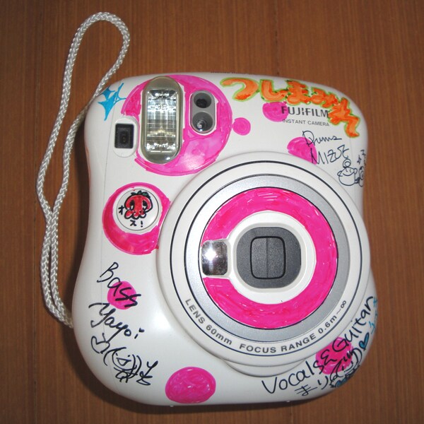 ホワイト×ピンクのカラフルなチェキ本体にはメンバーのサインが。