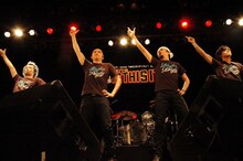 雑ながら息ピッタリのダンスで会場を沸かせた怒髪天。舞台裏の真実を明かすTwitter企画でも大活躍だったドラマー坂詰克彦（写真左から2番目）は、記者会見での「健康管理はどうなさっていますか？」という質問に、普段から行っているという謎の体操を披露した。