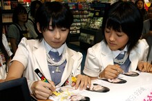 サインを書く福田花音（写真左）と、それを見つめる小川紗季（右）。