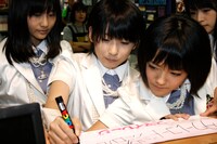 最後にタワーレコード渋谷店へのメッセージを書く福田花音（写真左から2番目）と、それを見つめるメンバー。