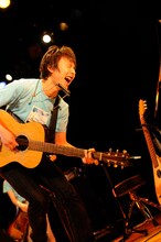 「アイス缶珈琲」のビデオクリップでサラリーマンに扮しているsuzumoku。所属レーベルWorld apartのオフィシャルYouTubeチャンネルでは、ビデオクリップをフルサイズで公開している。