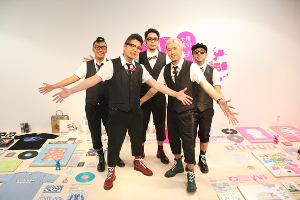 両手を広げて無数の展示品をアピールするRIP SLYME。