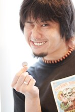 100円（インタビューテキスト販売価格）を握りしめ、夏休みのおこづかいをもらった少年のような笑みを浮かべるKen Yokoyama。