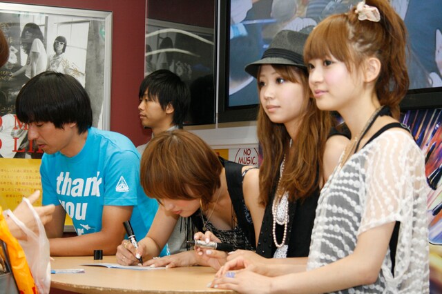 アルバム「thank you for the music!」のブックレットに、それぞれサインをするふかわりょうとCOSMETICS。