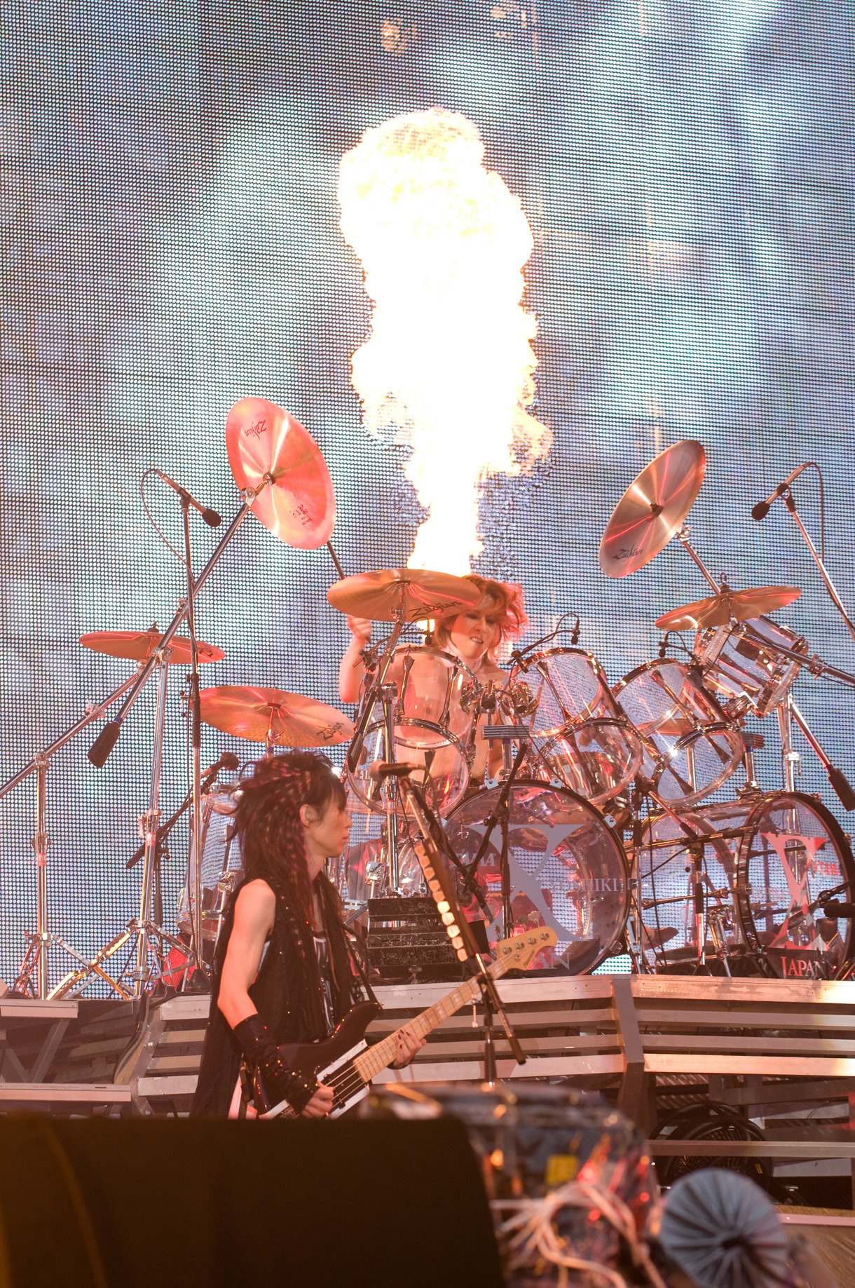 火柱の映像をバックに激しいプレイを披露するYOSHIKI。