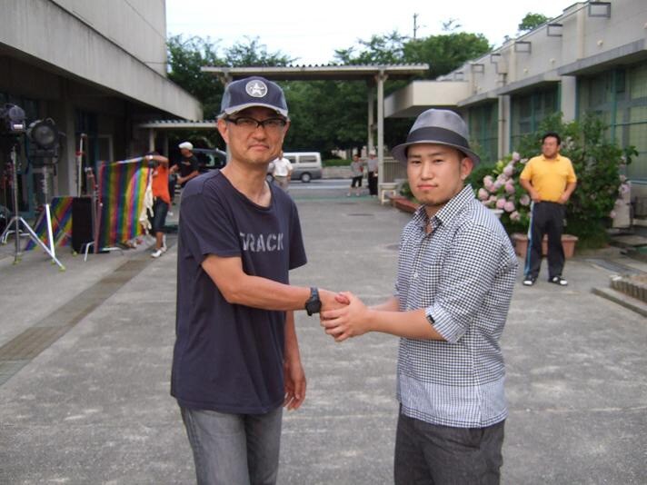 ガッチリ男同士の握手を交わす堤幸彦（写真左）とSunya（右）。