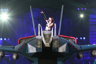 写真は西武ドーム公演「NANA MIZUKI LIVE GAMES」の様子。戦闘機「アルカディア7」がドームを突っ切った。