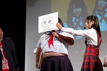 仲川遥香（写真右）が描いたミツコのイラストを、実際に長友（中央）の顔に被せたところ、他のメンバーは「似てるっ！」と大絶賛。