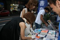 「超月刊バニラビーンズ 創刊2号」にサインを入れるレナ。