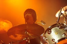 ドラムプレイ中も笑顔を絶やさないムードメーカー河邉徹（Dr）。