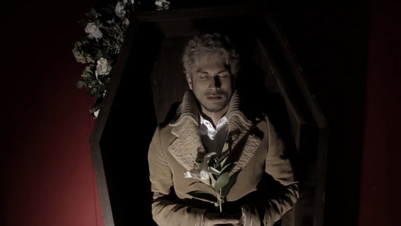 写真は新曲「アイシテル」ビデオクリップより。花を抱え棺おけに横たわる平井堅。