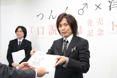 サインを入れた著書をファンに手渡すつんく♂。