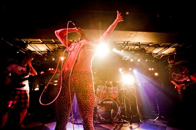 撃鉄のライブ写真。中央の豹柄レギンスを履いた半裸の男がボーカルの天野ジョージ。