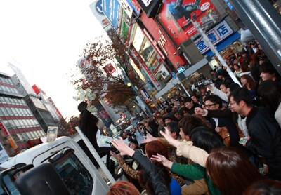渋谷センター街入口付近でさまざまな紙幣をばら撒くAL familia。
