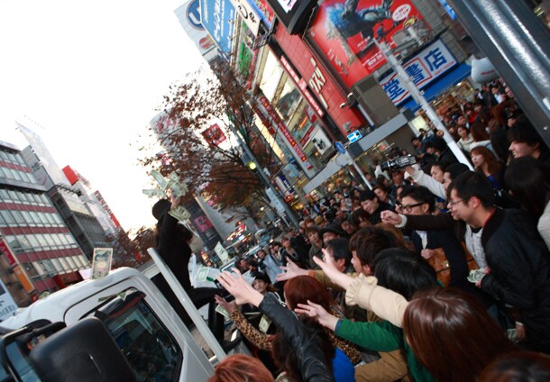 渋谷センター街入口付近でさまざまな紙幣をばら撒くAL familia。