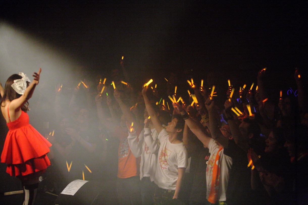 オレンジ色のサイリウムを高々と掲げるなっちゅりーにたち（photo: Mizushima Masaru）。