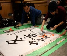 「冬至の日ライブ」の直筆看板にゆずの絵を書き入れる北川悠仁。