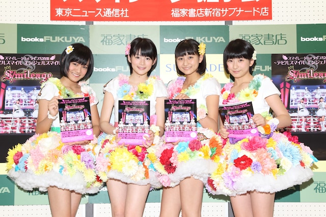 「1st LIVE写真集～デビルスマイル エンジェルスマイル」を手に、撮影に応じるスマイレージ。