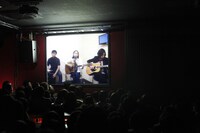 生中継の画面に見入るオーディエンス。