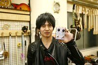 手作りエフェクターを手に微笑む古村大介。