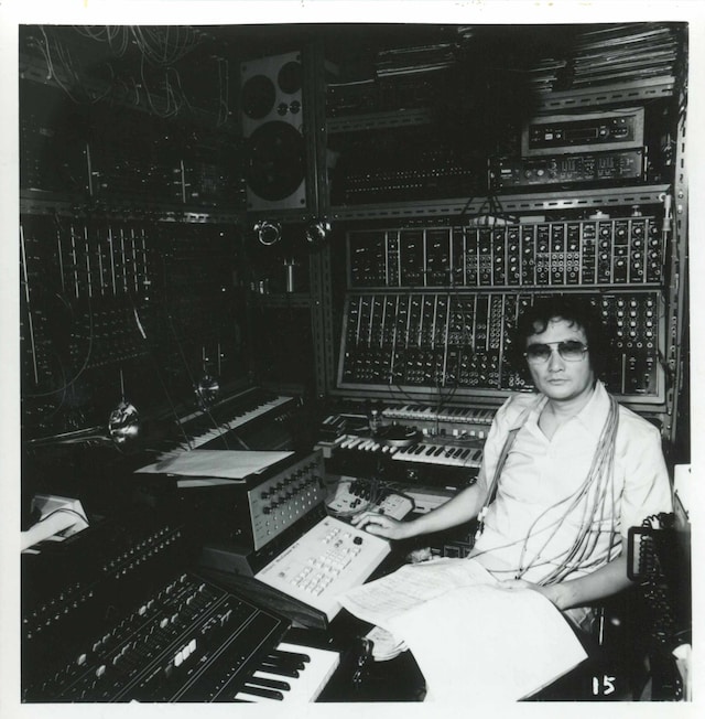 1970年代、壁一面を覆うシンセサイザーに囲まれた冨田勲。