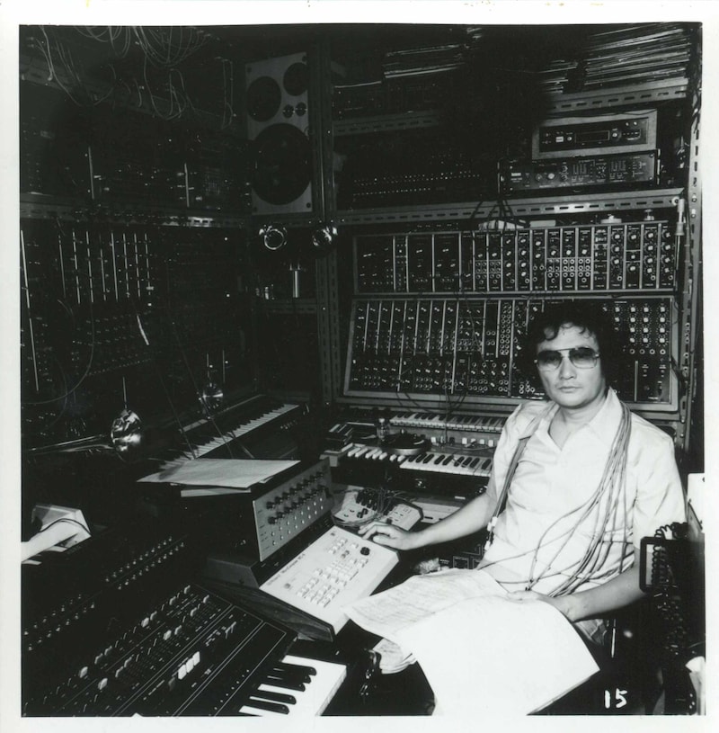 1970年代、壁一面を覆うシンセサイザーに囲まれた冨田勲。