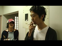 映画「シンクロニシティ」のワンシーン。左が百々和宏演じるデザイナーの緒方。