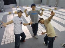 3000枚の「3000」スタンプジャケットを背に記念撮影するスチャダラパーの3人。