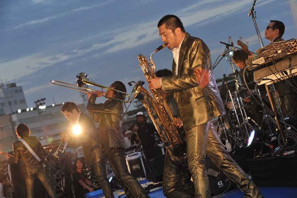 夕闇迫る大井競馬場でライブを繰り広げる東京スカパラダイスオーケストラ。