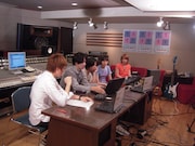 写真は「生ラマ」配信中のスタジオの様子。コメントが表示されるPCを観るLAMAの4人。