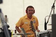 ドラムを叩く奥田民生。黄色い「カンタビレ」ワークシャツがお似合い。