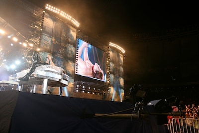 クリスタルピアノの上でマイクを握りしめるYOSHIKI。